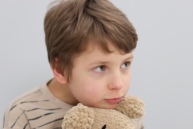 Autism concept. Lonely little boy with toy on grey background