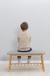 Autism concept. Lonely little boy on bench at home, back view