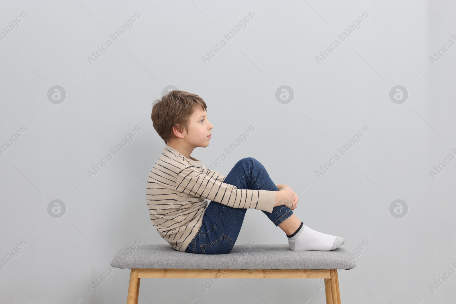 Photo of Autism concept. Lonely little boy on bench at home