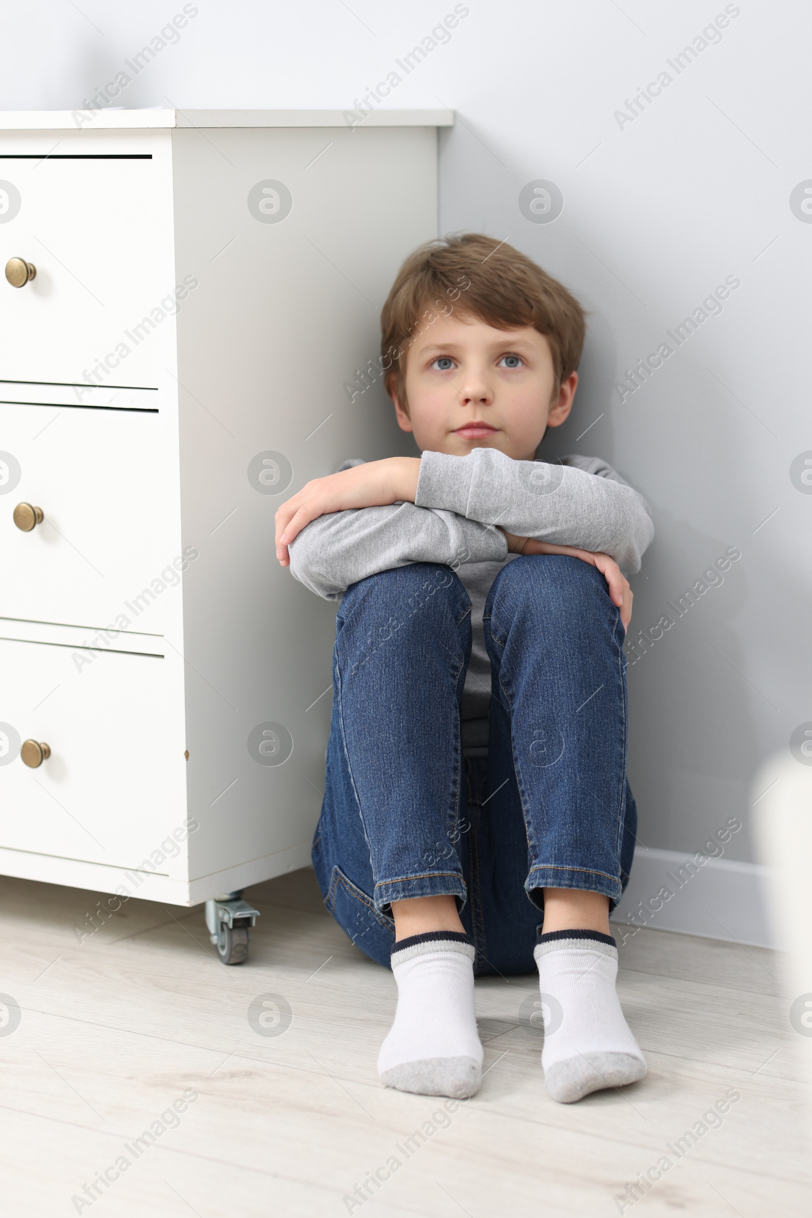 Photo of Autism concept. Lonely little boy on floor near grey wall at home