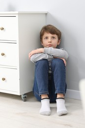 Photo of Autism concept. Lonely little boy on floor near grey wall at home