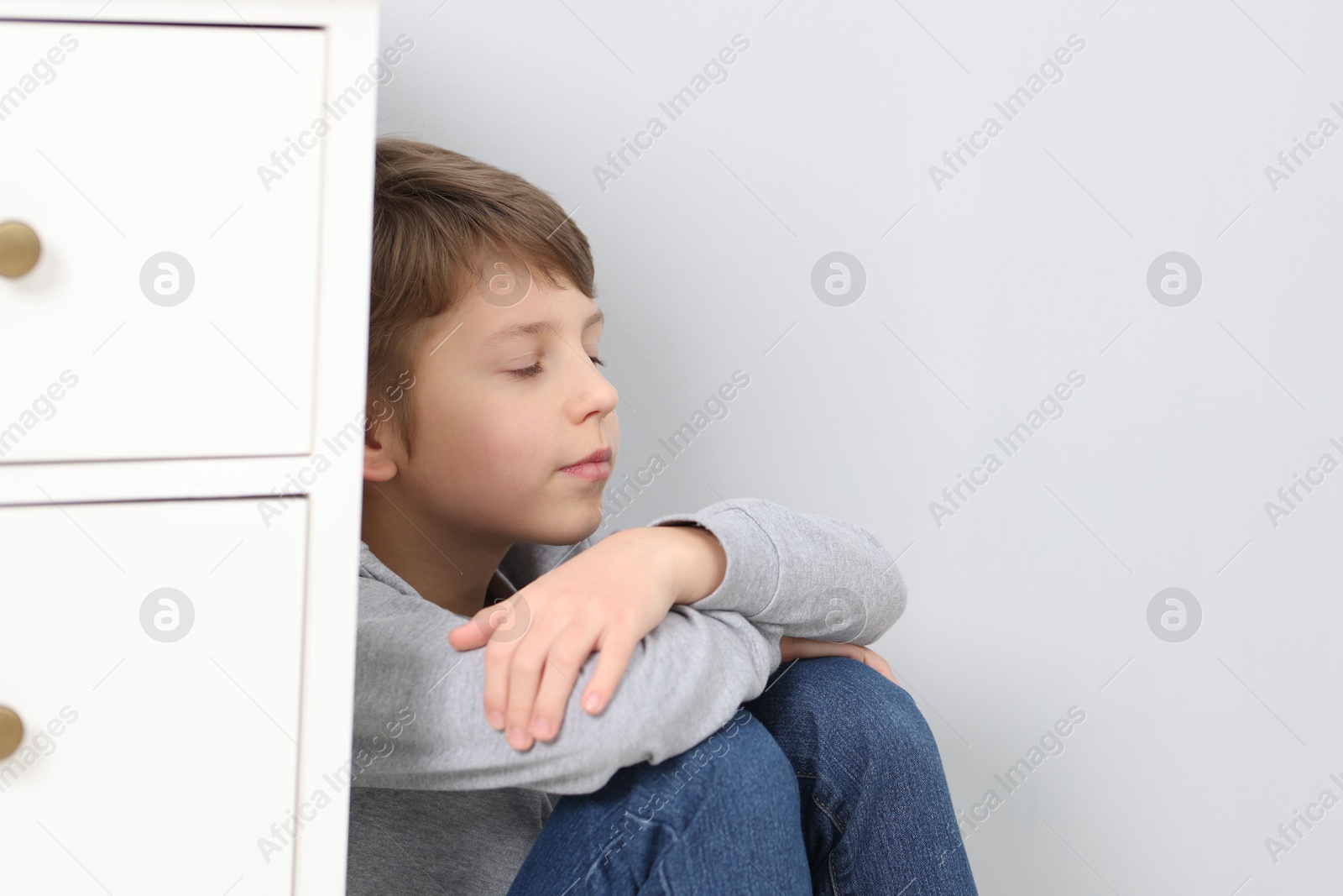 Photo of Autism concept. Lonely little boy near grey wall at home