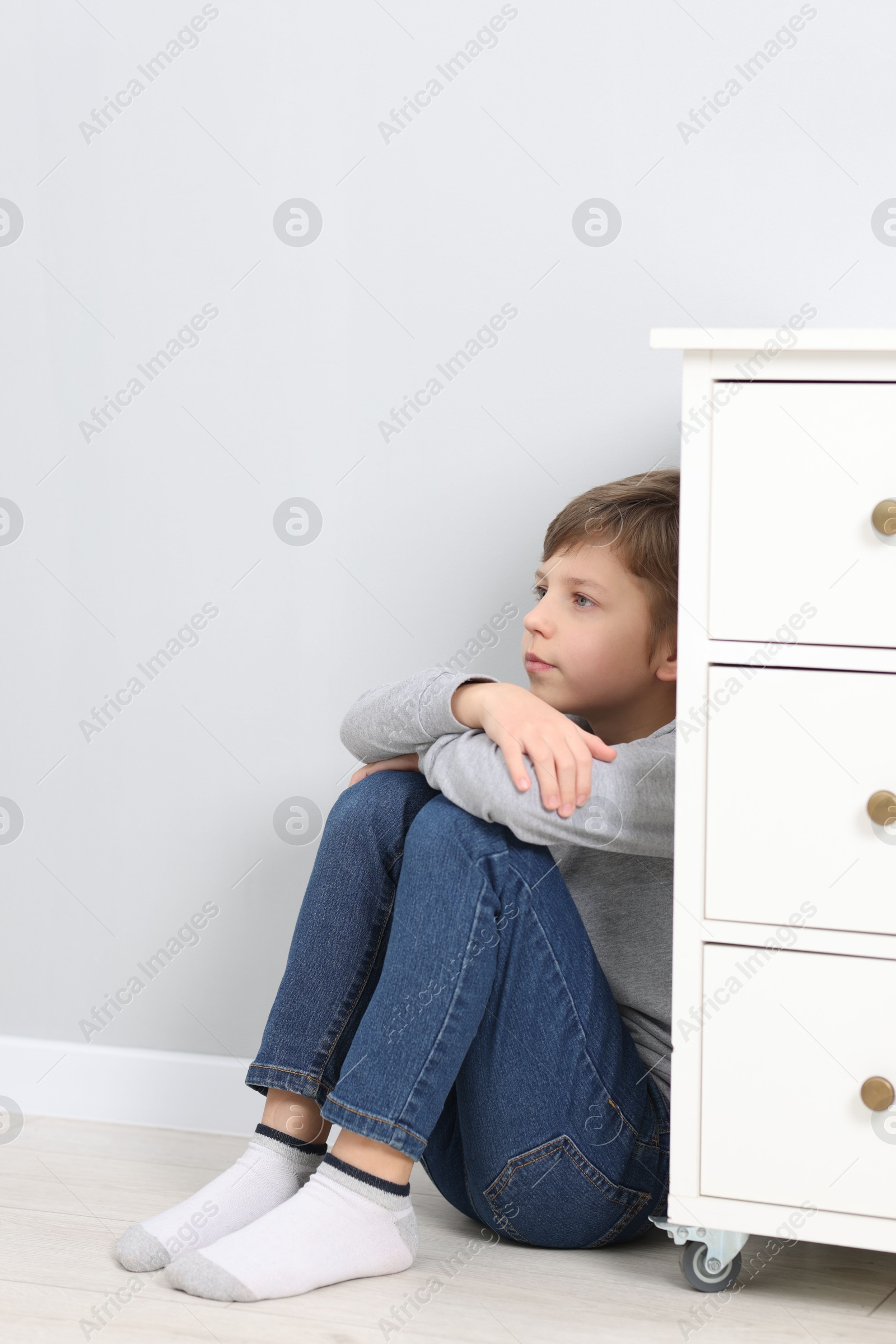 Photo of Autism concept. Lonely little boy on floor near grey wall at home