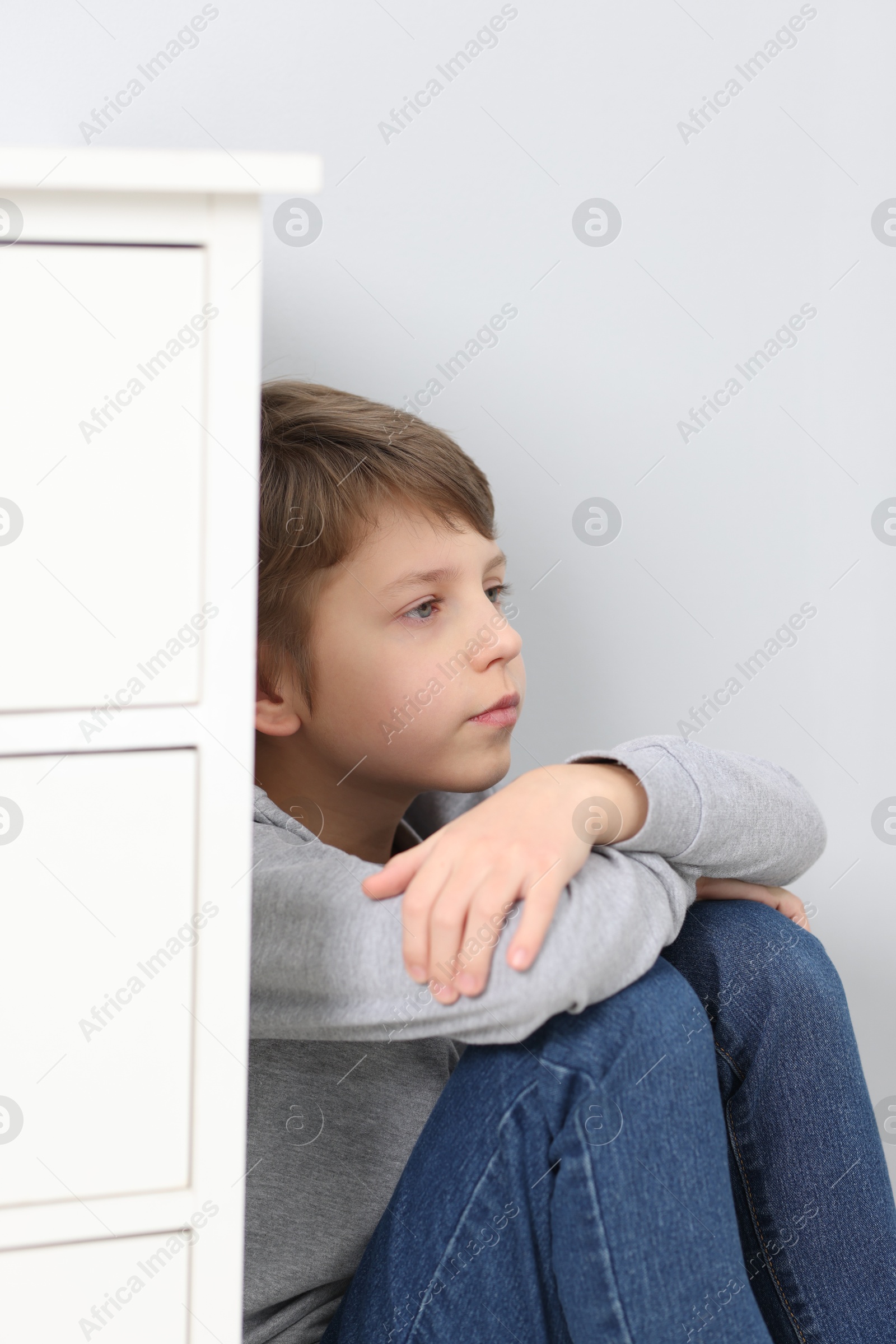 Photo of Autism concept. Lonely little boy near grey wall at home