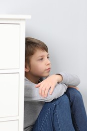 Autism concept. Lonely little boy near grey wall at home