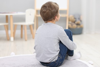 Autism concept. Lonely little boy on floor at home