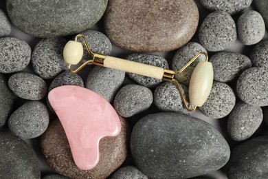 Photo of Face roller and gua sha tool on stones, top view