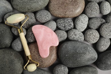 Photo of Face roller and gua sha tool on stones, top view