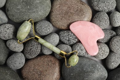 Photo of Face roller and gua sha tool on stones, top view