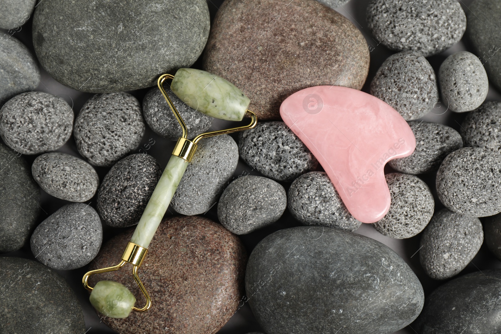 Photo of Face roller and gua sha tool on stones, top view