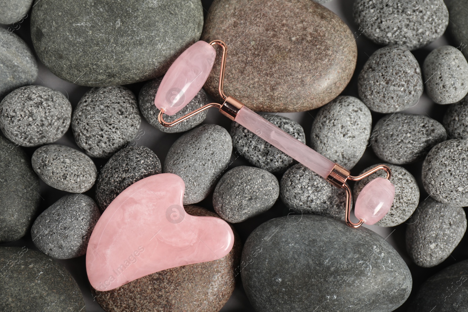 Photo of Face roller and gua sha tool on stones, top view