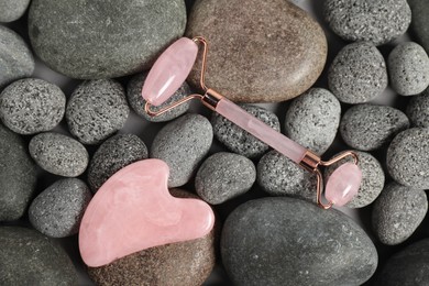 Photo of Face roller and gua sha tool on stones, top view