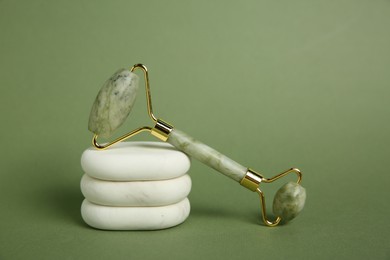 Photo of Face roller and massage stones on green background