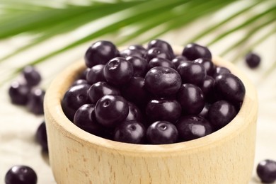 Photo of Ripe acai berries in bowl on table, closeup