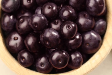 Photo of Ripe acai berries in wooden bowl, top view