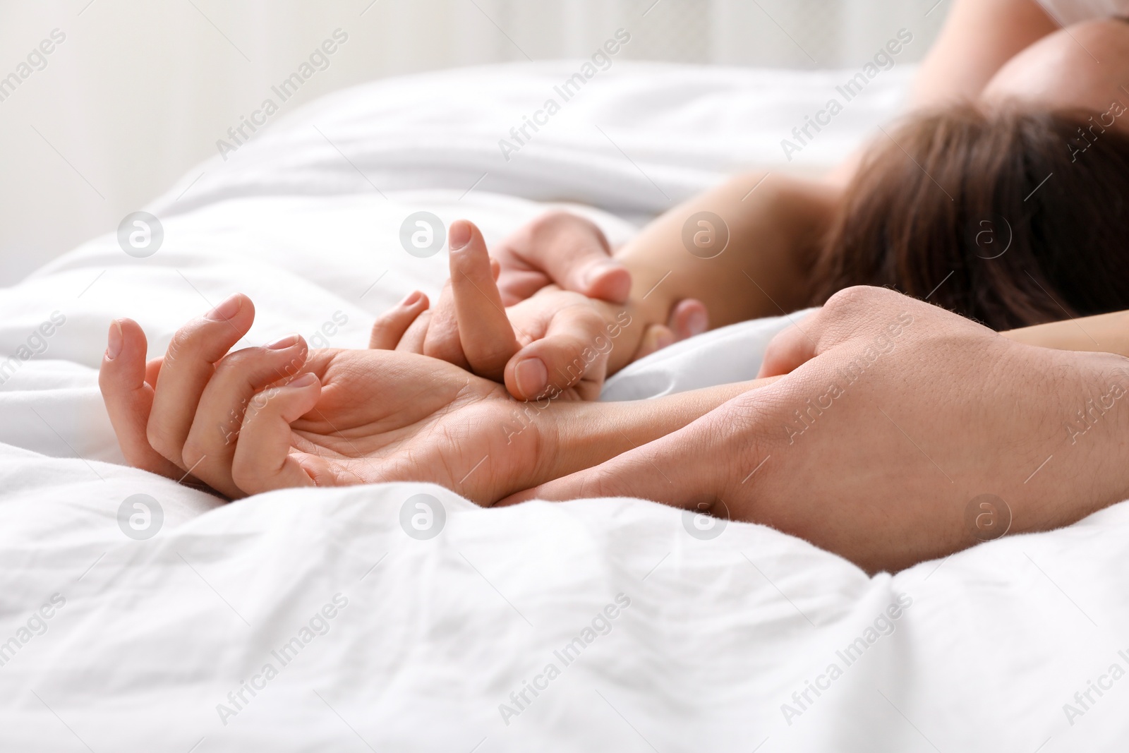 Photo of Lovely couple holding hands in bed, closeup