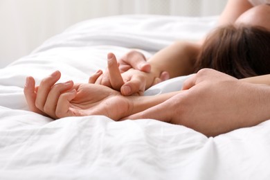 Lovely couple holding hands in bed, closeup