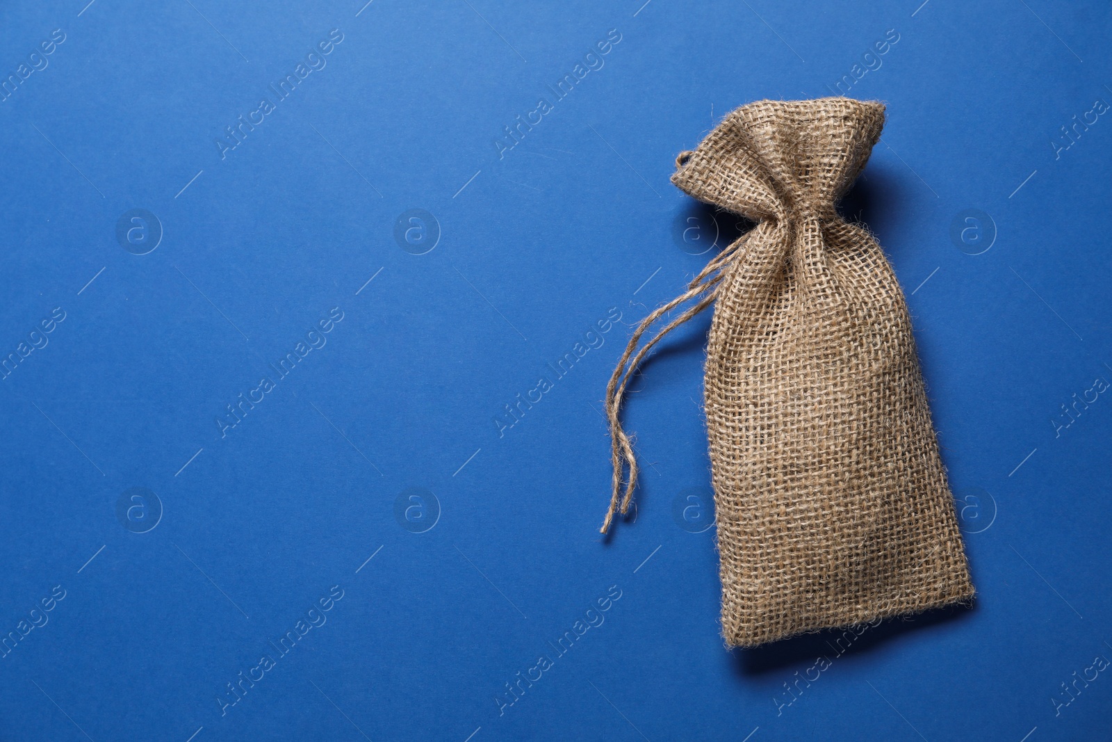 Photo of One burlap sack on blue background, top view. Space for text