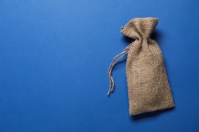 Photo of One burlap sack on blue background, top view. Space for text