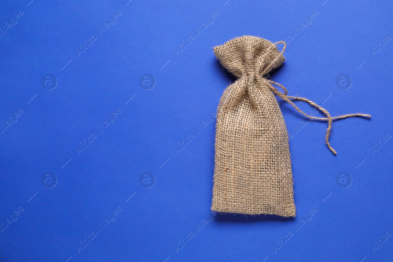 Photo of One burlap sack on blue background, top view. Space for text