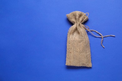 Photo of One burlap sack on blue background, top view. Space for text