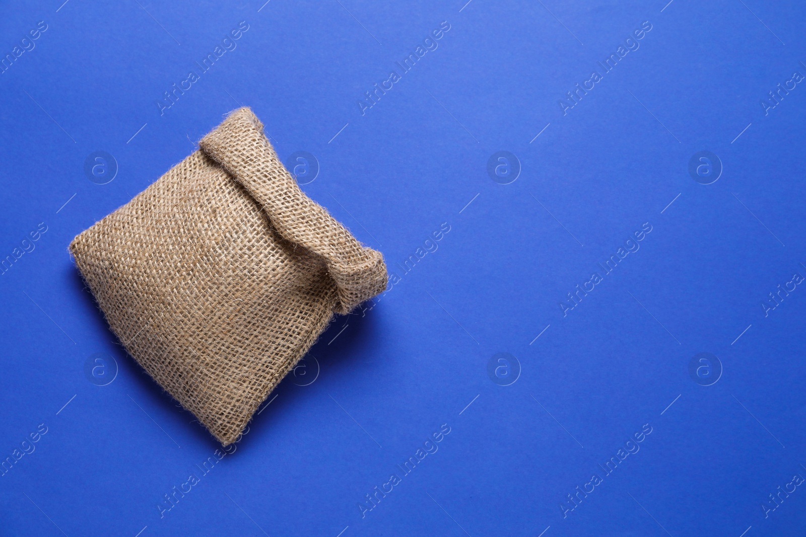 Photo of One burlap sack on blue background, top view. Space for text