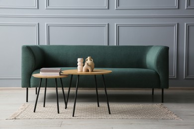 Stylish sofa, books and decor elements on nesting tables in room