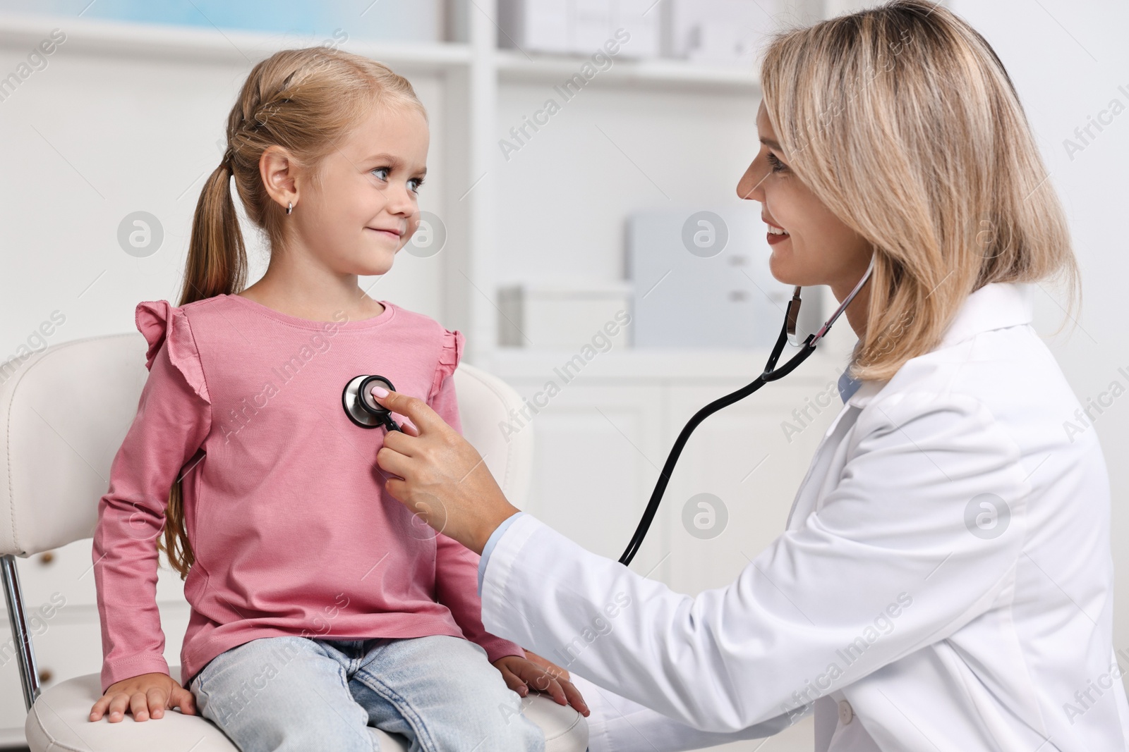 Photo of Doctor examining little girl with stethoscope in hospital