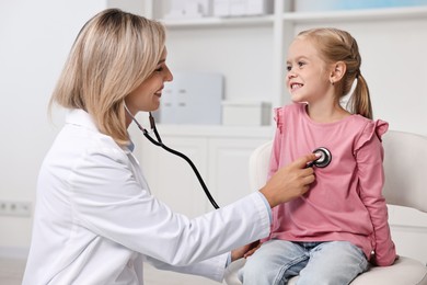 Doctor examining little girl with stethoscope in hospital