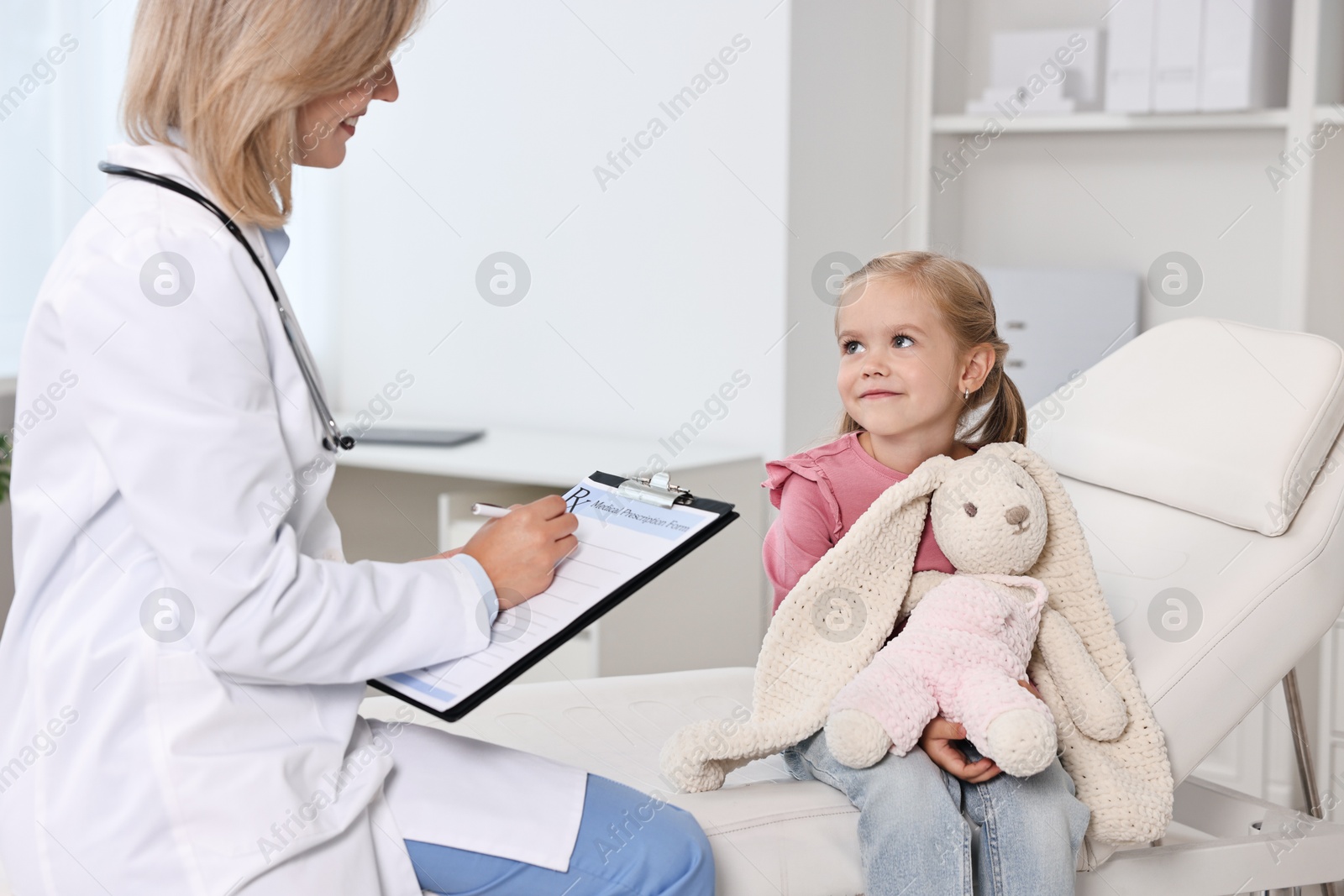 Photo of Doctor consulting little girl with toy in hospital, closeup