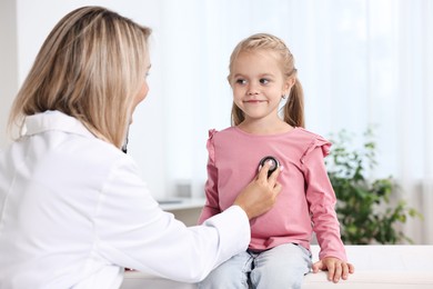 Doctor examining little girl with stethoscope in hospital