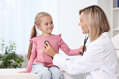 Doctor examining little girl with stethoscope in hospital