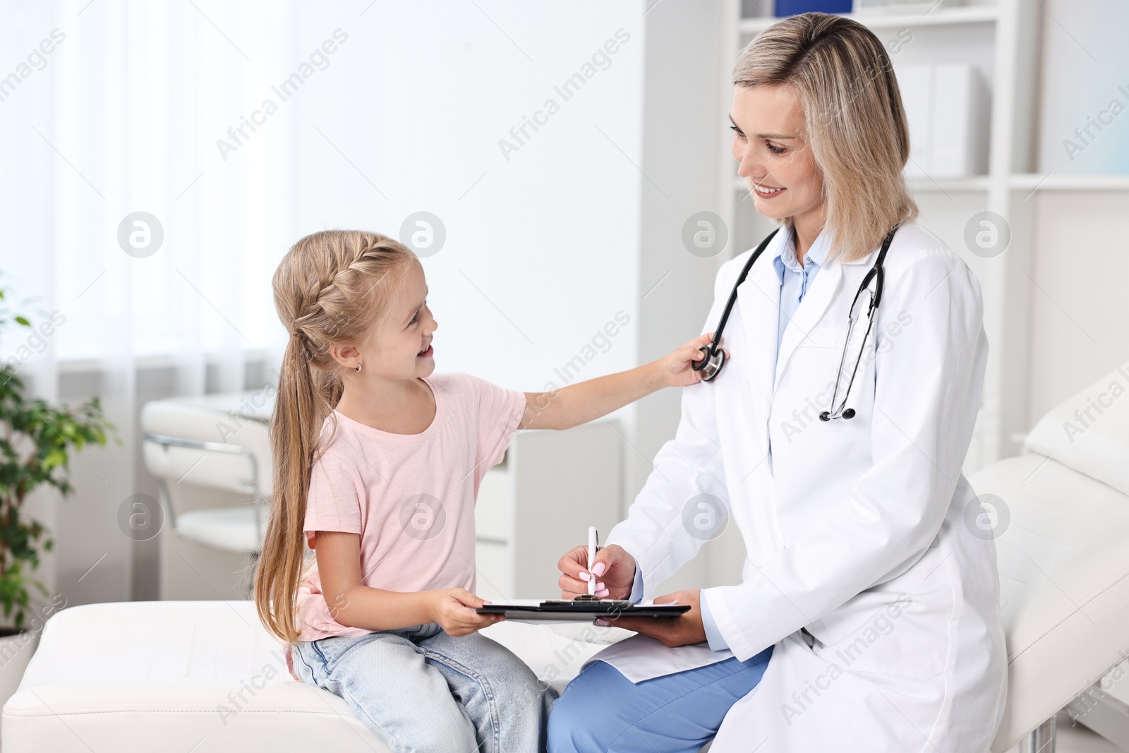 Photo of Doctor with clipboard consulting little girl in hospital