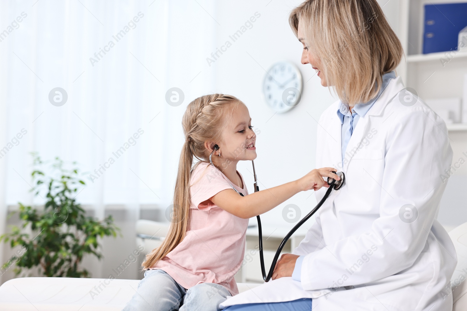 Photo of Little girl with stethoscope and doctor having fun in hospital