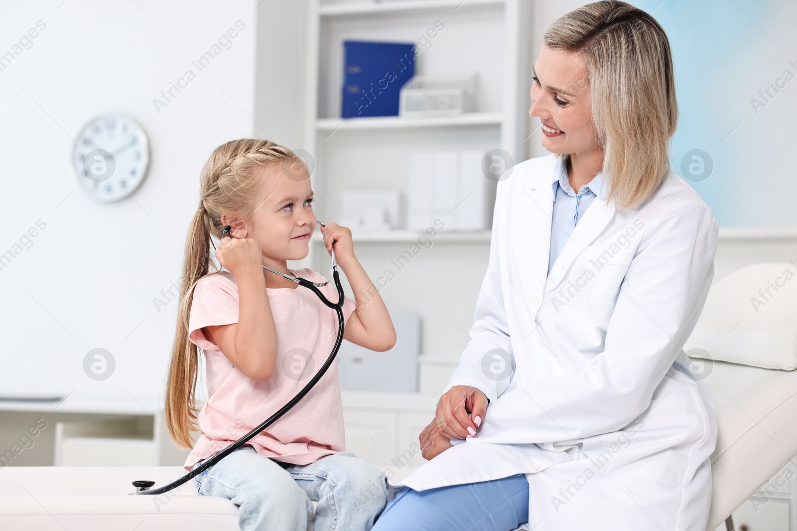 Photo of Little girl with stethoscope and doctor having fun in hospital