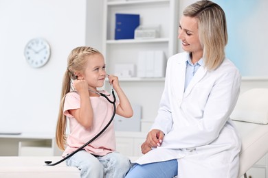 Little girl with stethoscope and doctor having fun in hospital