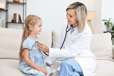 Photo of Doctor examining little girl with stethoscope indoors