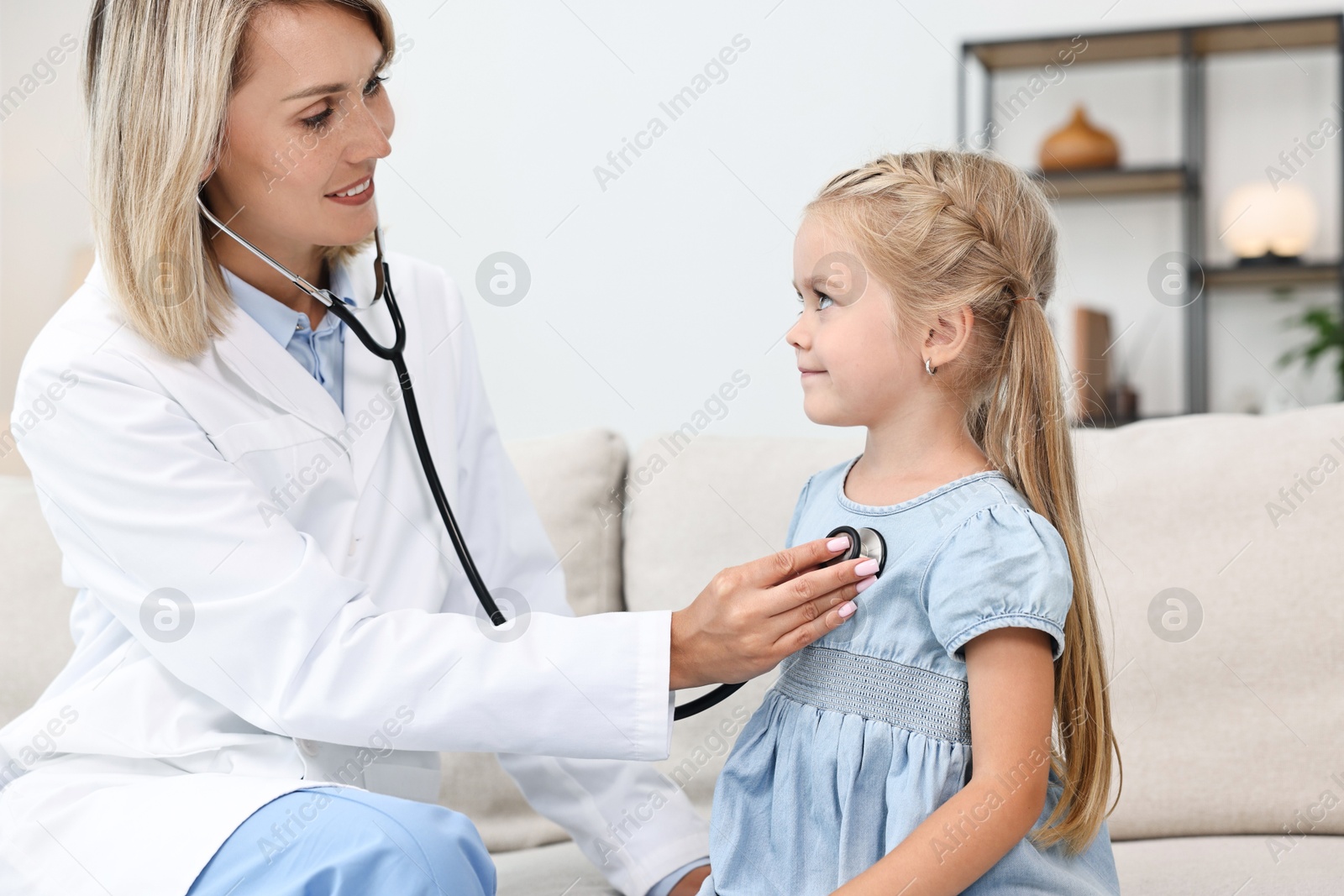 Photo of Doctor examining little girl with stethoscope indoors