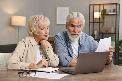 Photo of Pension savings. Senior couple planning budget at wooden table indoors