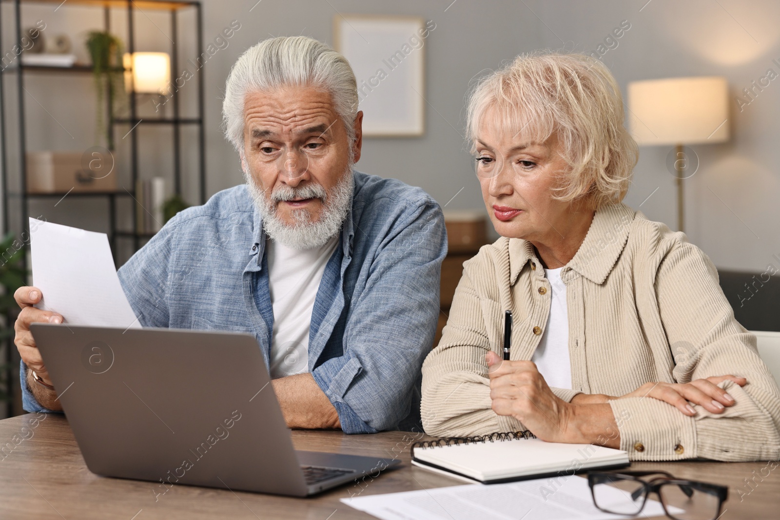 Photo of Pension savings. Senior couple planning budget at wooden table indoors