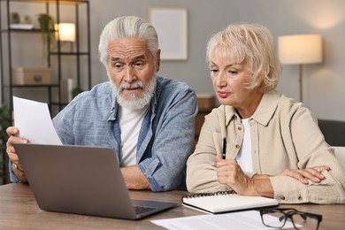 Photo of Pension savings. Senior couple planning budget at wooden table indoors