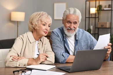 Pension savings. Senior couple planning budget at wooden table indoors