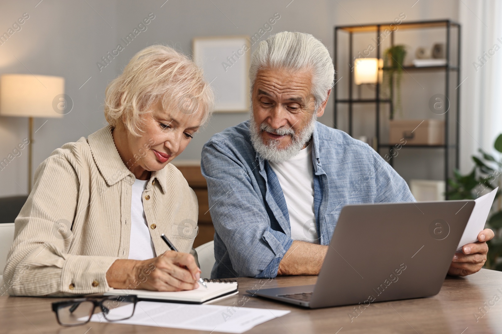 Photo of Pension savings. Senior couple planning budget at wooden table indoors