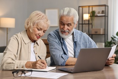 Pension savings. Senior couple planning budget at wooden table indoors