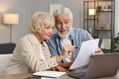 Photo of Pension savings. Senior couple planning budget at wooden table indoors