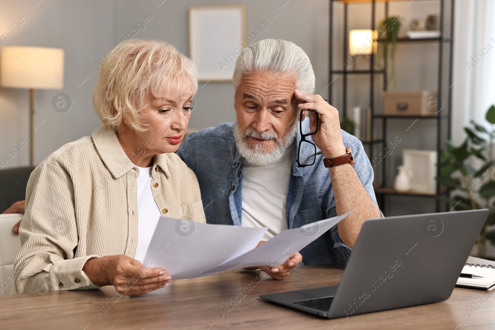 Photo of Pension savings. Senior couple planning budget at wooden table indoors