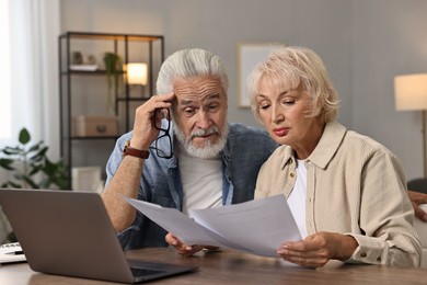 Pension savings. Senior couple planning budget at wooden table indoors