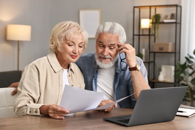 Photo of Pension savings. Senior couple planning budget at wooden table indoors