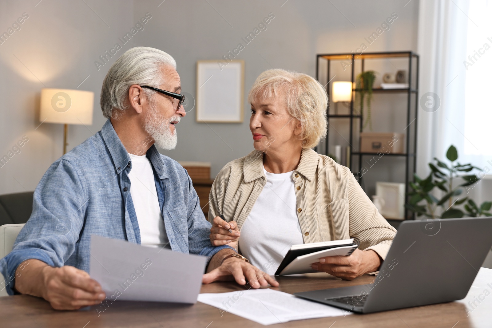 Photo of Pension savings. Senior couple planning budget at wooden table indoors