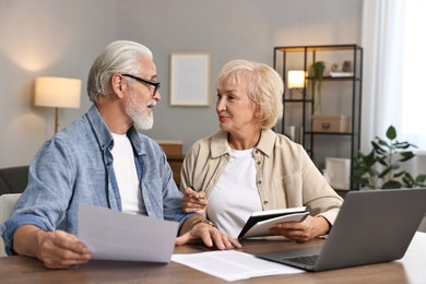 Pension savings. Senior couple planning budget at wooden table indoors